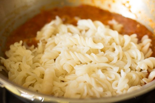 cooked pasta added to arrabiata sauce in pan