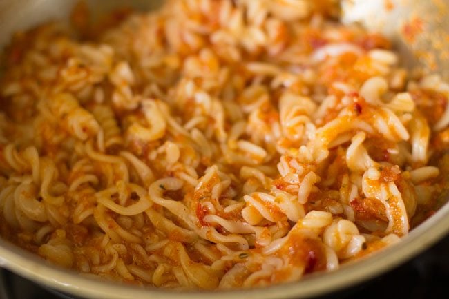 mixing pasta with arrabiata sauce in pan