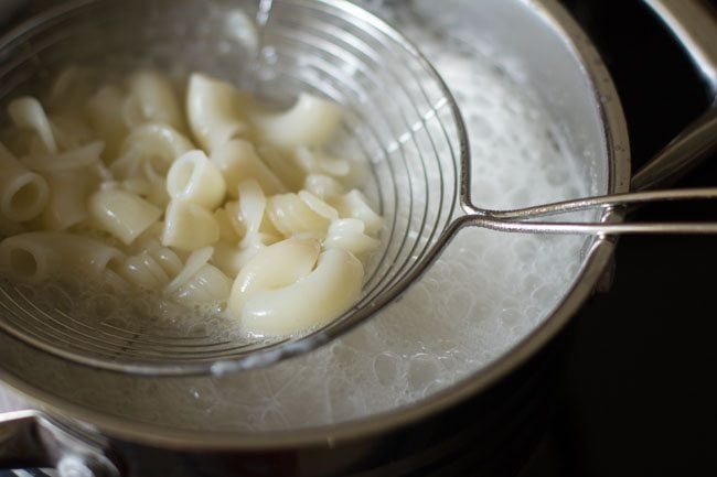 pasta cooked and being removed with a strainer