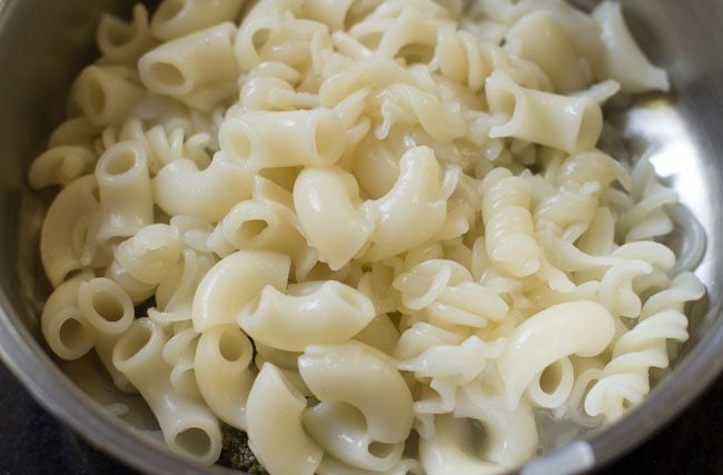 cooked pasta added to the bowl containing the basil pesto sauce