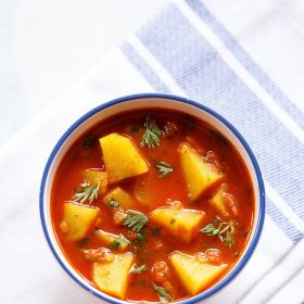 caril de batata numa tigela branca com bordos azuis sobre um guardanapo branco com bordos azuis