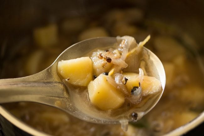 softened potatoes with onions and spices in a spoon. 