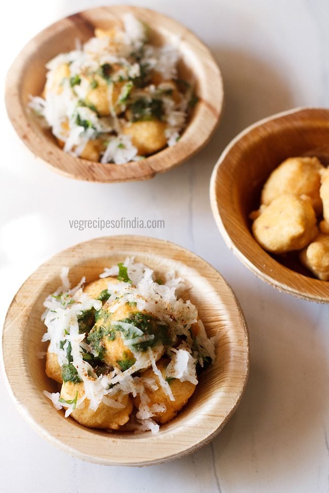 ram ladoo topped with green chutney, grated radish-coriander leaves and served in individual small bowls with text layovers. 