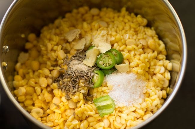 soaked dals, chopped ginger, chopped green chili, cumin seeds, asafoetida and salt added to a blender jar. 