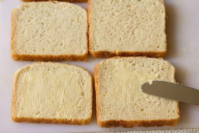 applying butter on bread slices on a board
