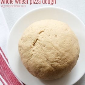 whole wheat pizza dough on a white plate with a red and white striped kitchen towel.