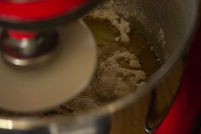 preparing whole wheat pizza dough recipe using stand mixer and dough hook.