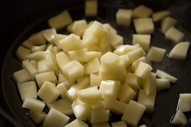 adding potatoes to the pan