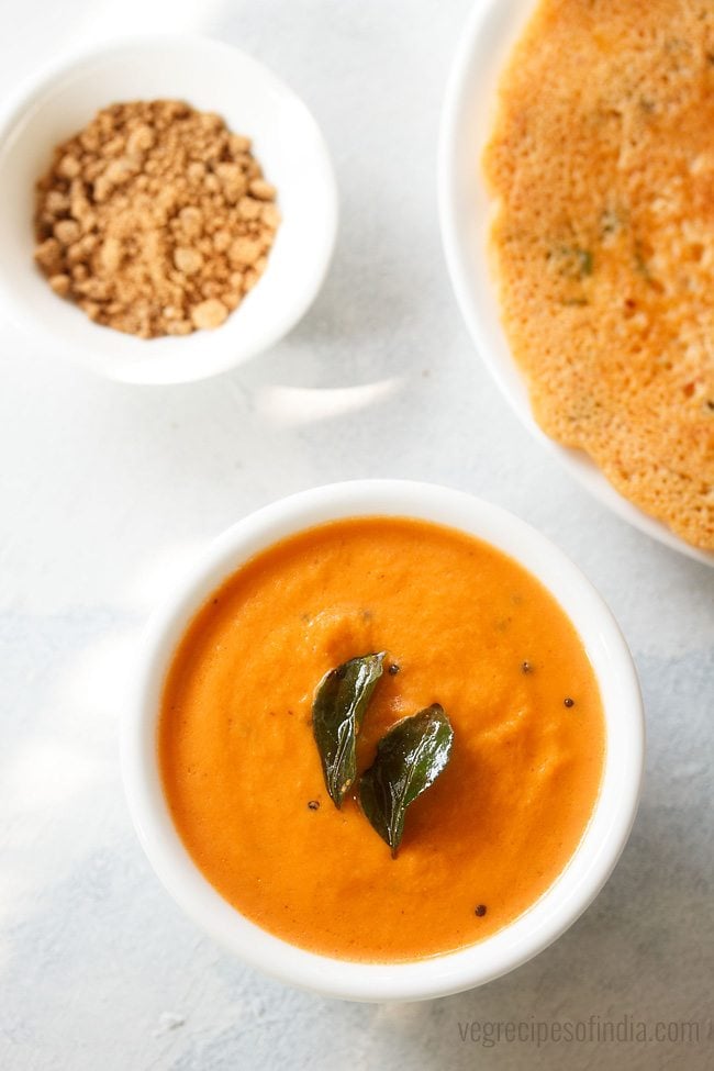 carrot chutney served in a bowl with dosa