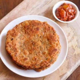 carrot paratha served on a white plate with a side of pickle.