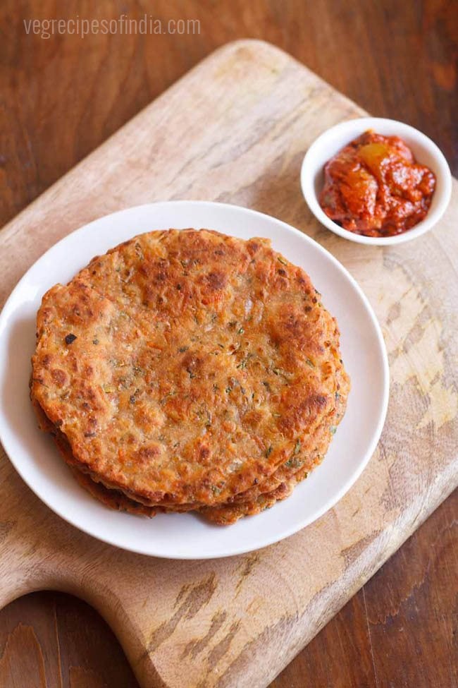 carrot paratha served on a white plate with a side of pickle.