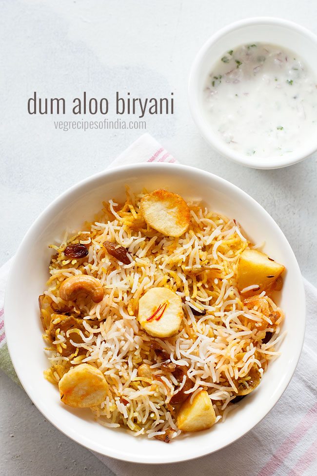 aloo biryani served in a white plate. with a bowl of raita kept on the top left side and text layovers. 
