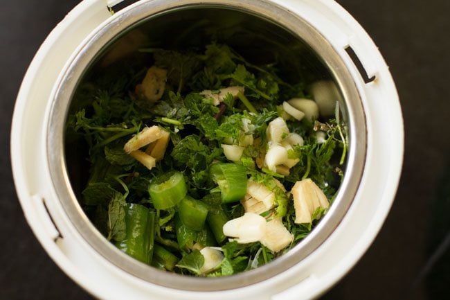 green chilies, chopped coriander leaves, chopped mint leaves, roughly chopped ginger and roughly chopped garlic cloves added to a grinder jar. 