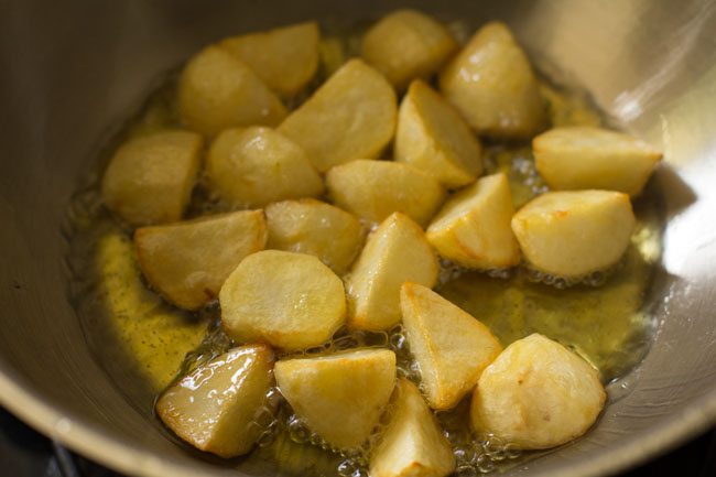 frying potatoes in hot ghee till 90% cooked. 