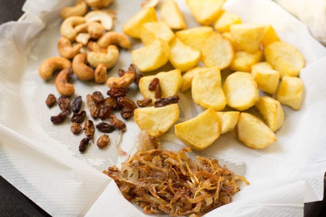 some fried onions kept with other fried ingredients on kitchen paper towel. 