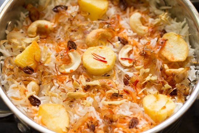 repeat the layers with the remaining gravy, cooked rice, fried ingredients, saffron water and top with kewra water. 