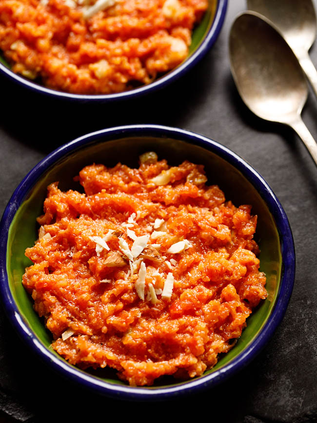 instant pot gajar halwa served in a two dark green small plates with two brass spoons at the sides