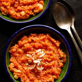 instant pot gajar halwa served in a two dark green small plates with two brass spoons at the sides
