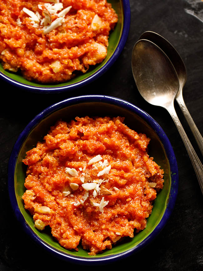 instant pot gajar halwa served in a two dark green small plates with two brass spoons at the sides