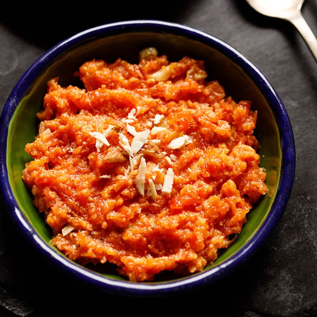 instant pot gajar halwa topped with chopped almonds in a dark blue lined green enamel plate