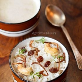 kerala nei choru garnished with fried cashews, fried raisins, fried onions, coriander leaves and served in a blue rimmed bowl with text layovers.