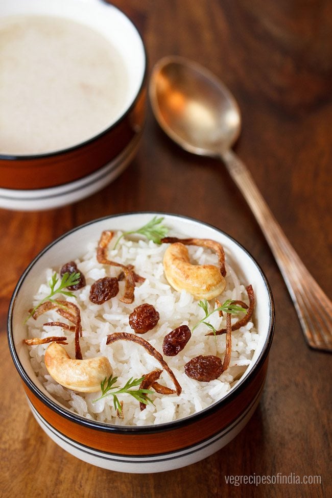 neychoru garnished with fried cashews, fried raisins, fried onions, coriander leaves and served in a blue rimmed bowl with text layovers.