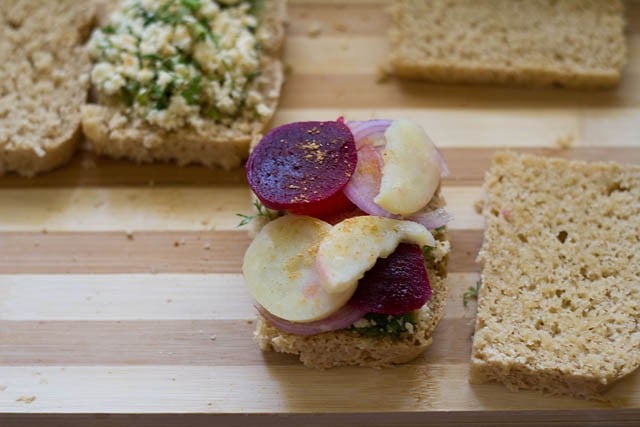 one buttered bread slice topped with some prepared paneer stuffing and boiled vegetable slices. 