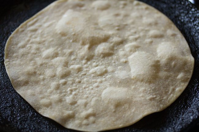 roti is flipped again, exposing a dry side.