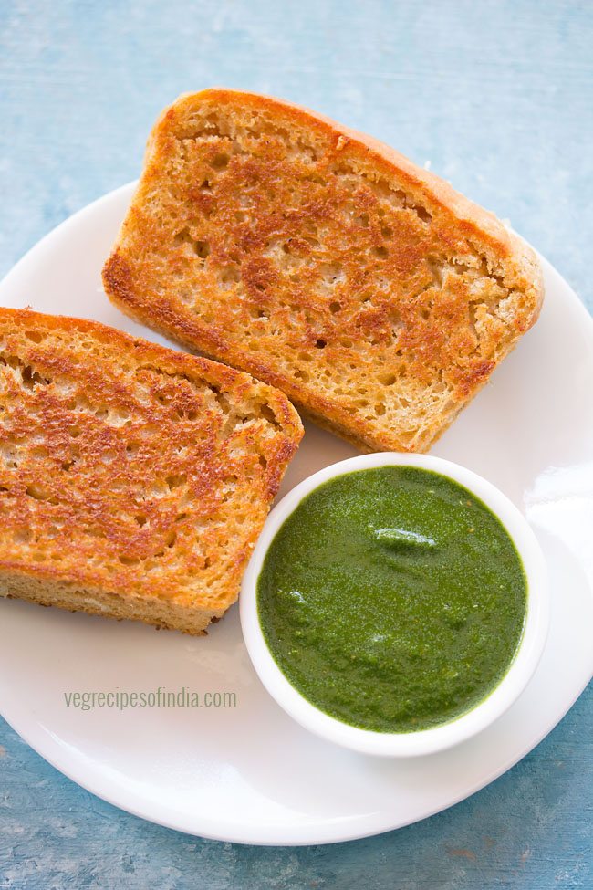 mint chutney served in a bowl with sandwich on a plate
