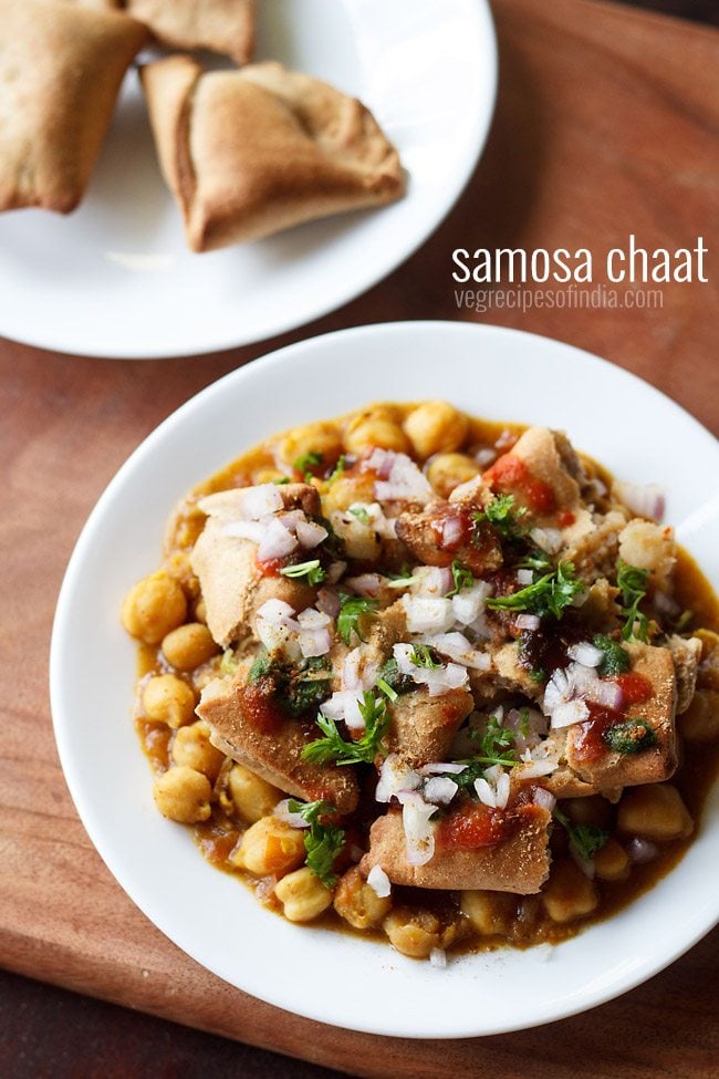 samosa chaat served on a white plate with a plate of samosas kept on the top right side and text layover.