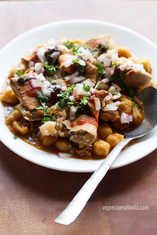 samosa chana chaat served on a white plate with spoon