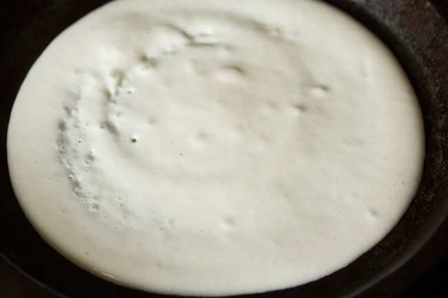 batter spread into a medium-thick or thick uttapam.