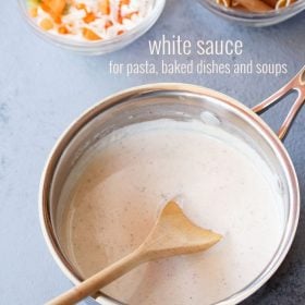 white sauce in a saucepan with wooden spoon inside.