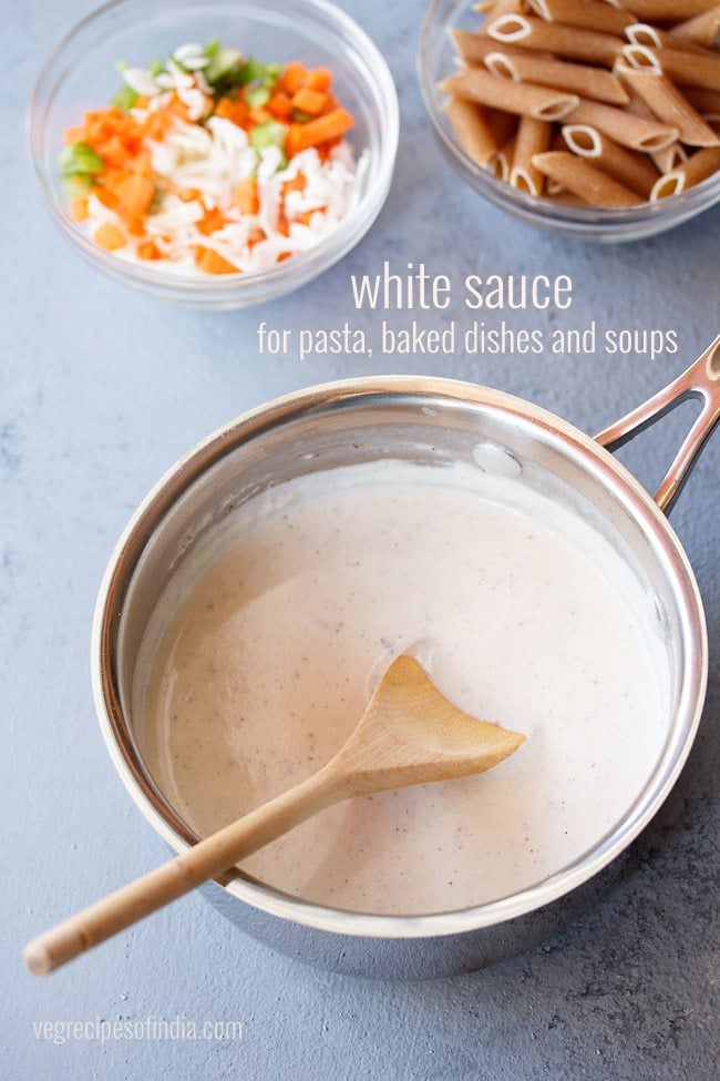 white sauce in a saucepan with wooden spoon inside.