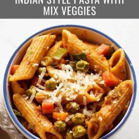 masala pasta garnished with grated cheese and served in a blue rimmed ceramic bowl with text layovers.