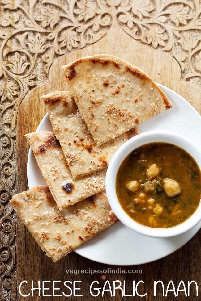 cheese garlic naan cut into wedges and served on a white plate with a bowl of curry kept on the right side.