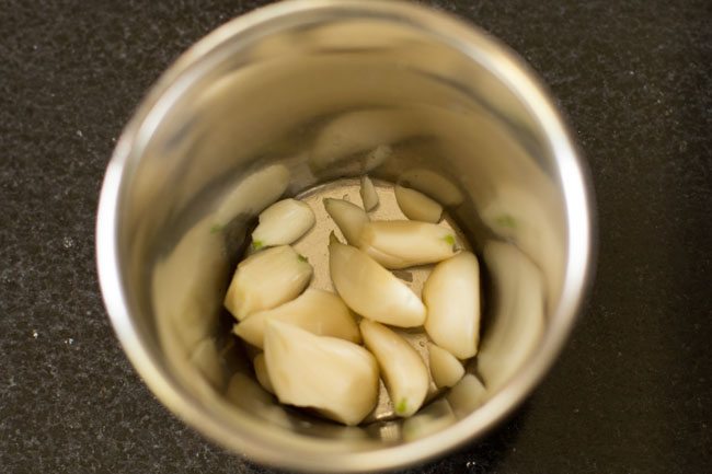 large garlic cloves added to a mortar. 