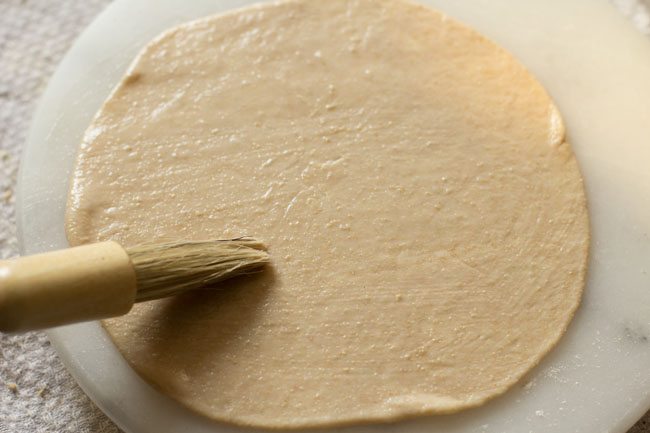 brushing water on rolled stuffed naan. 