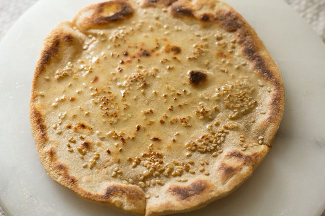 butter spread on cooked cheese garlic naan. 