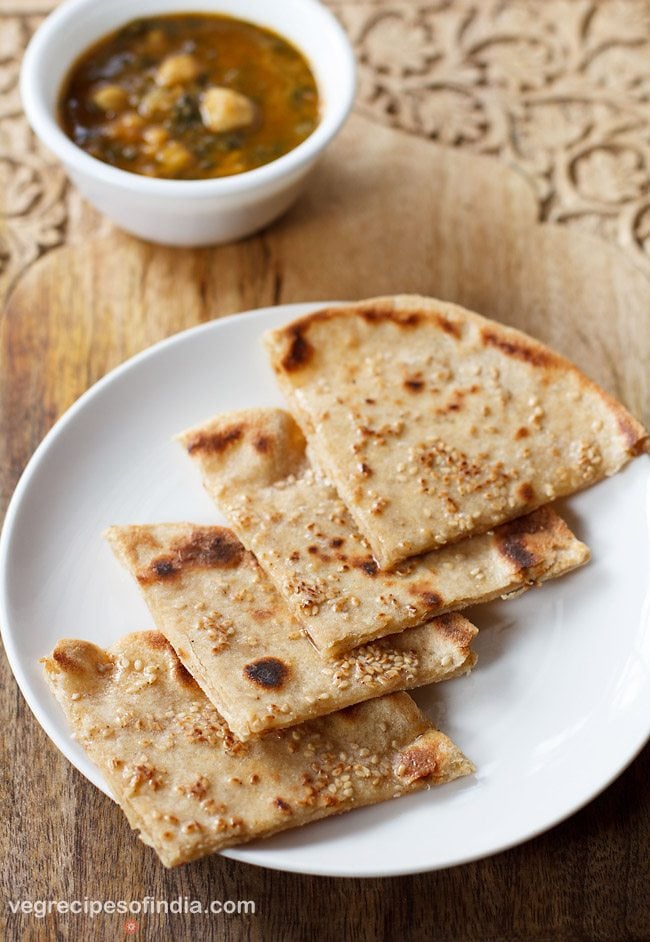 cheese garlic naan cur into wedges and served on a white plate. 