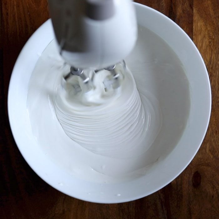 whipping cream being whipped in a white bowl