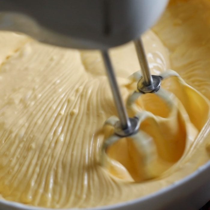 mango mixture and whipped cream being mixed with the electric beater