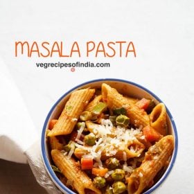 masala pasta garnished with grated cheese and served in a blue rimmed ceramic bowl with text layovers.