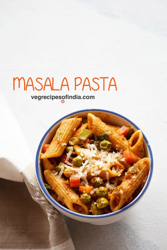 masala pasta garnished with grated cheese and served in a blue rimmed ceramic bowl with text layovers.
