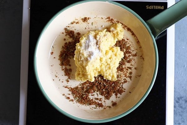 moong dal paste on top of spices in pan. 