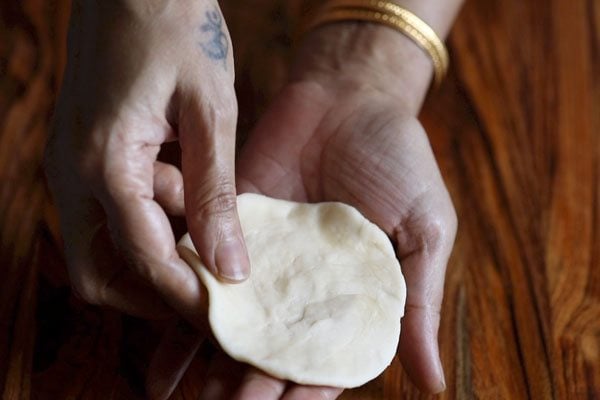flattened dough in hands. 