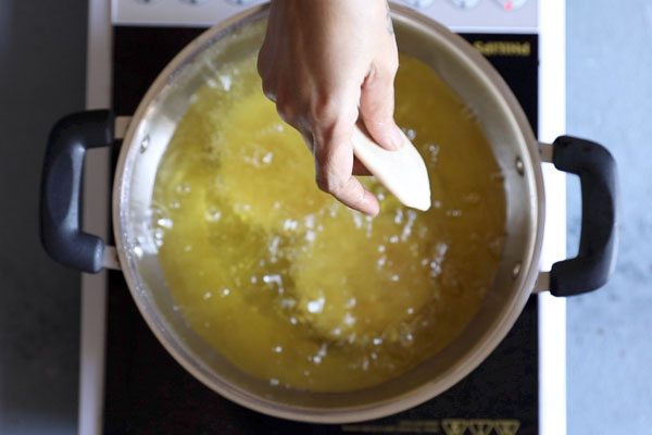 dal kachori being placed in hot oil in a kadai. 