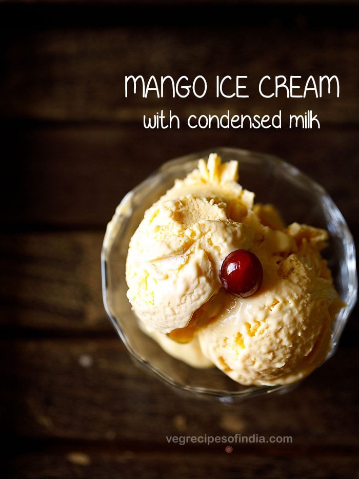 mango ice cream scoops in an ice cream bowl topped with a red cherry on a wooden tray