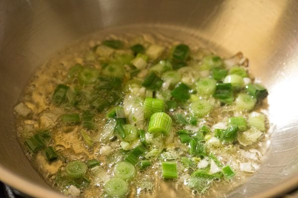 sautéing finely chopped spring onions in hot oil in pan. 
