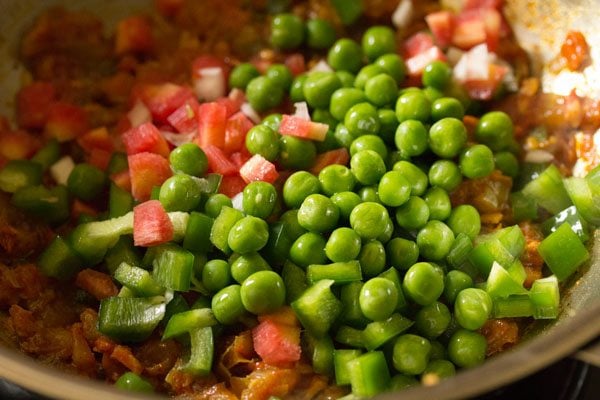 finely chopped carrots and capsicum, and green peas added to the pan. 